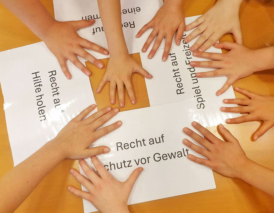 Viele Kinderhände auf Zetteln mit Schlagworten zu Kinderrechten