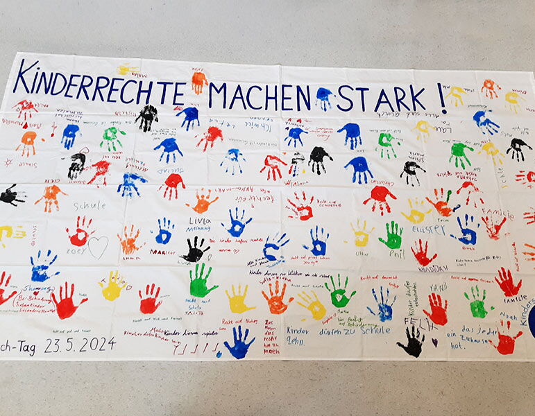 Textilbanner "Kinderrechte machen stark!" mit vielen bunten Handabdrücken