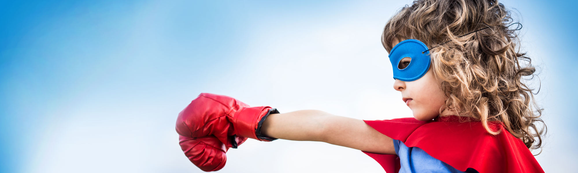 Kind mit Cape, Augenmaske und Boxhandschuh