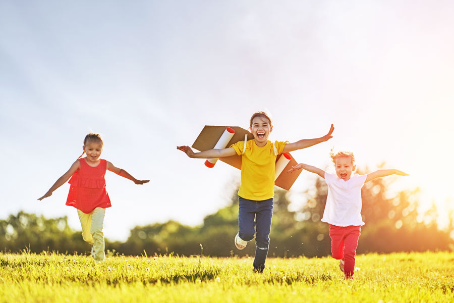 Bild: fröhliche Kinder laufen über eine Sommerwiese