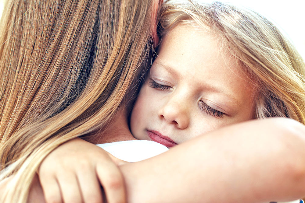 Kind umarmt Frau mit geschlossenen Augen