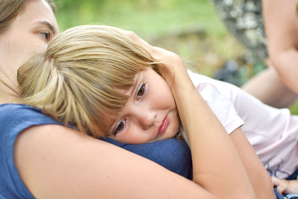 Kleines Mädchen liegt auf dem Bauch im Arm der Mutter