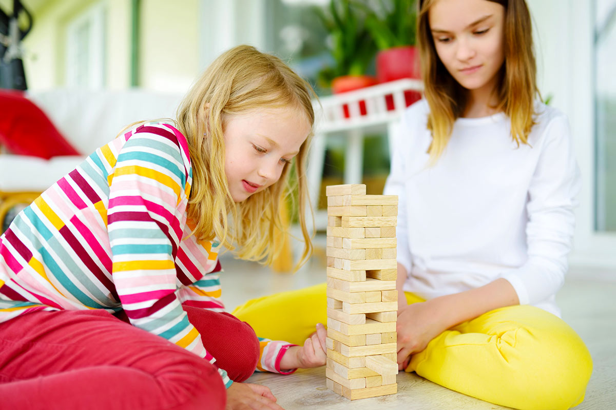 Kinder sitzen auf dem Teppich und spielen Jenga