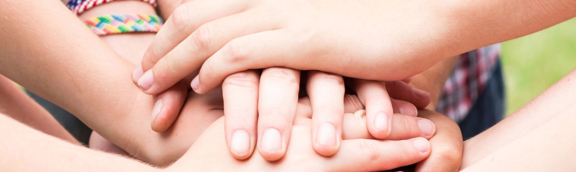 Mehrere Hände von Kindern und Erwachsenen liegen übereinander